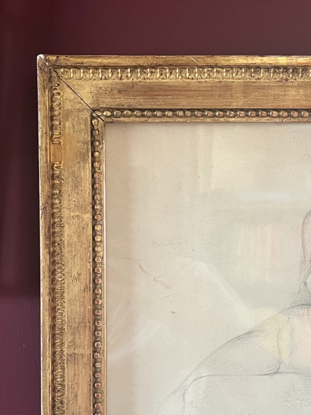 A pencil life drawing depicting a seated female nude, displayed inside a gilded wood frame with decorative beaded details. View II