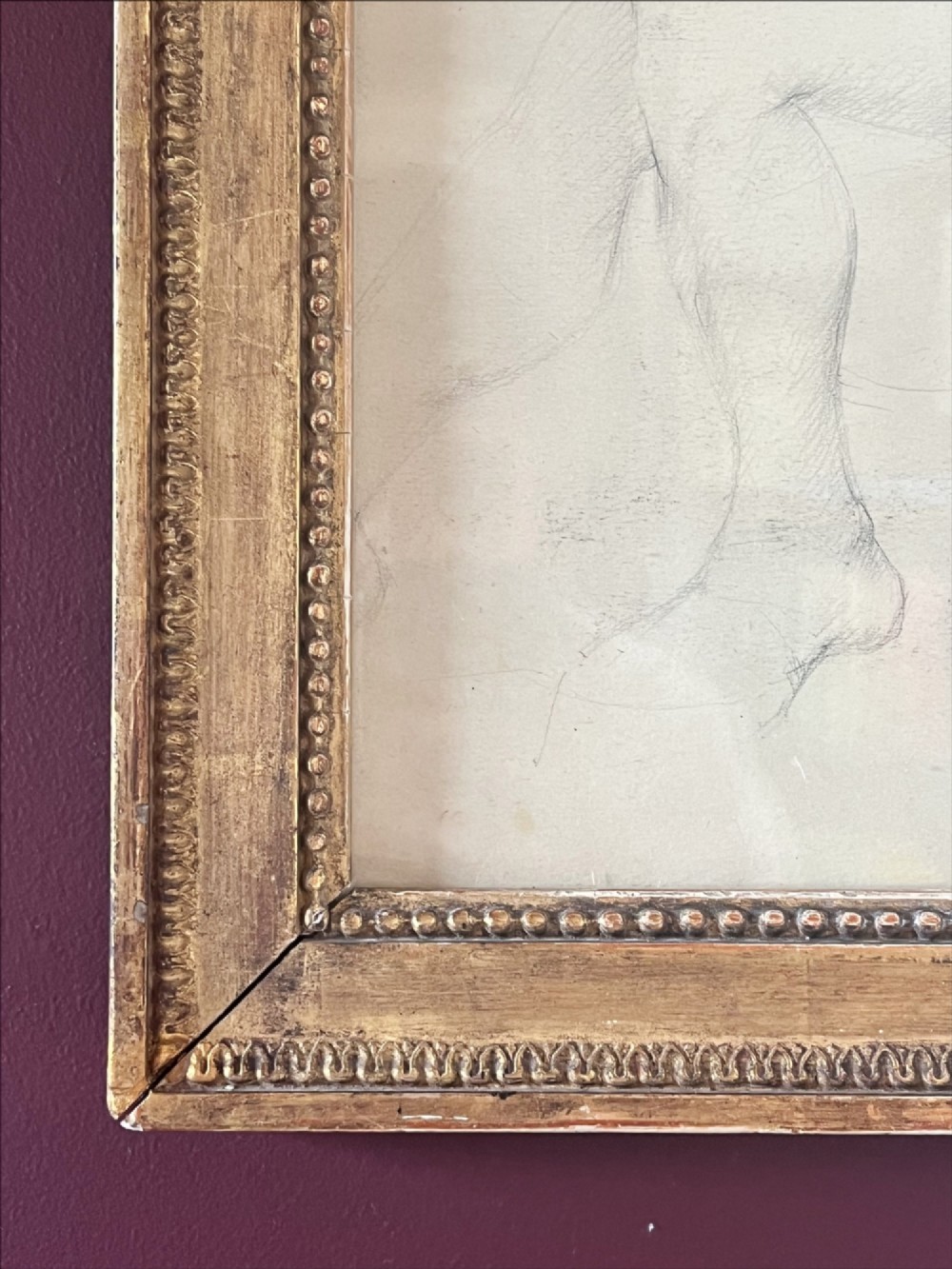 A pencil life drawing depicting a seated female nude, displayed inside a gilded wood frame with decorative beaded details. View IV