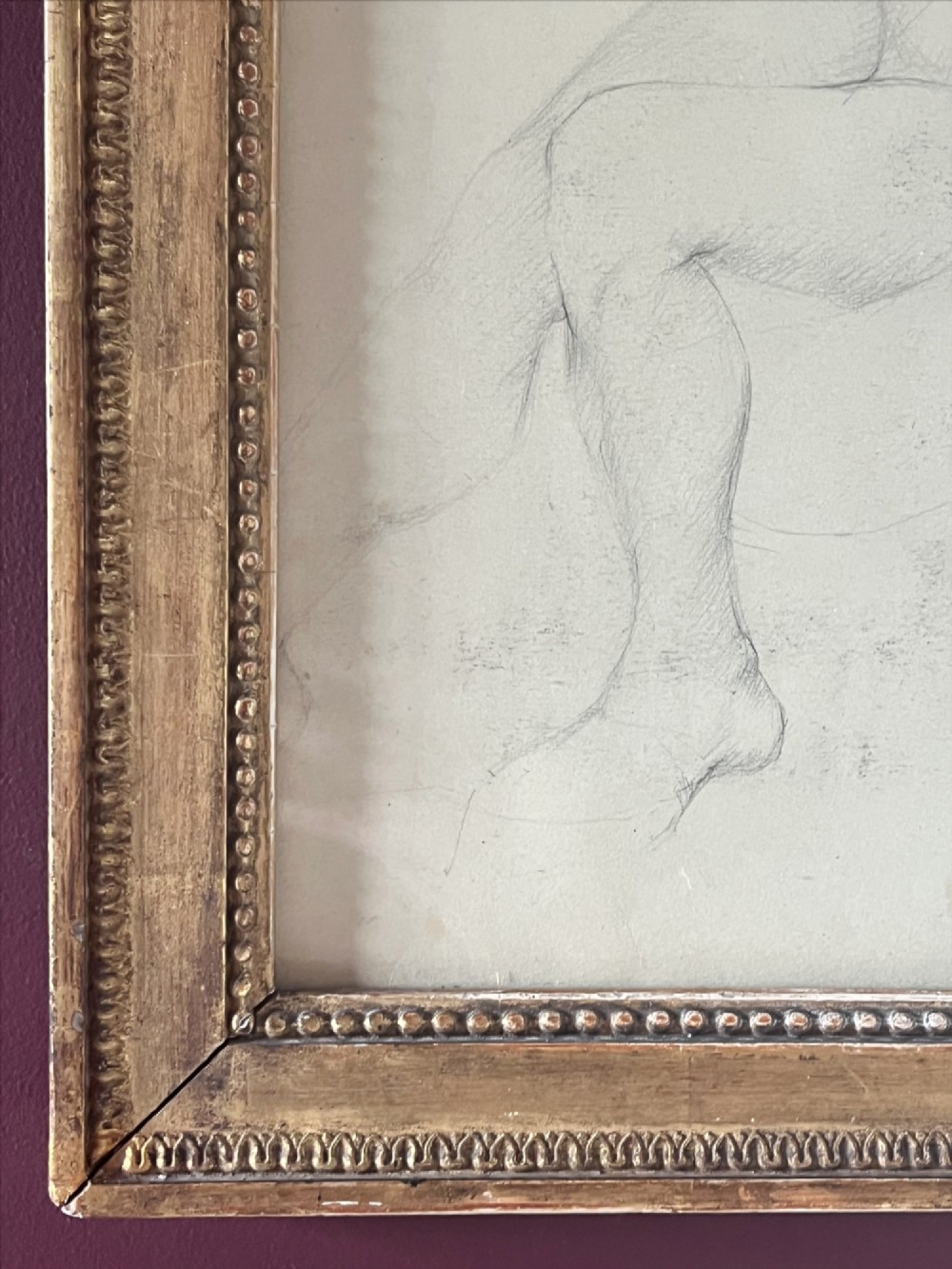 A pencil life drawing depicting a seated female nude, displayed inside a gilded wood frame with decorative beaded details. View V