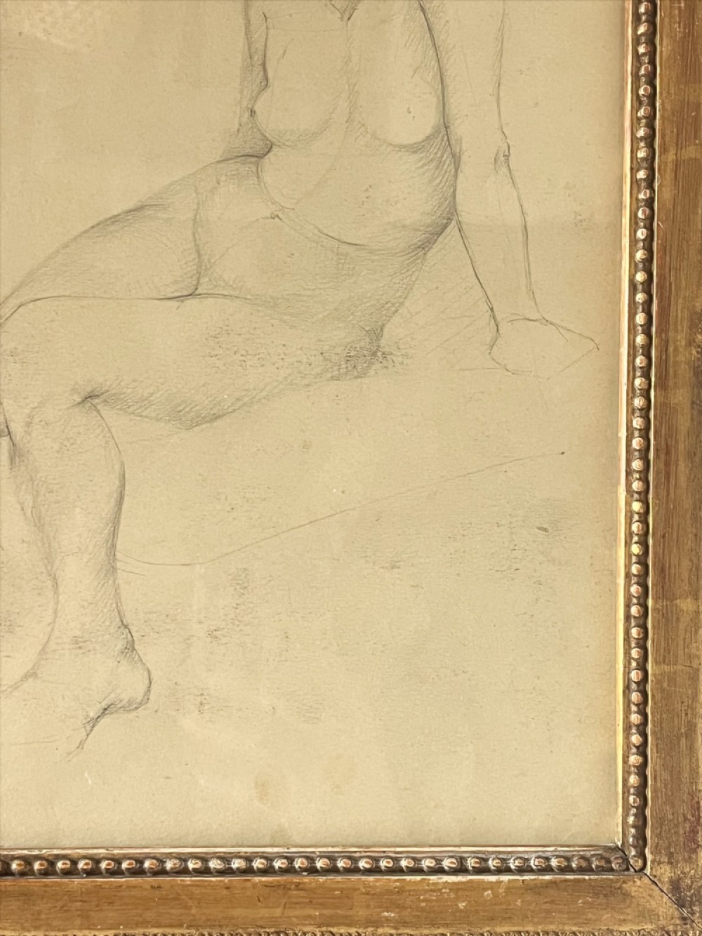 A pencil life drawing depicting a seated female nude, displayed inside a gilded wood frame with decorative beaded details. View VII