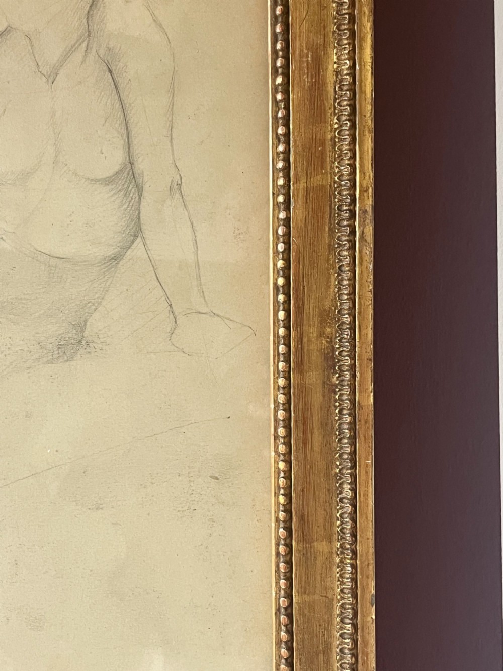 A pencil life drawing depicting a seated female nude, displayed inside a gilded wood frame with decorative beaded details. View X