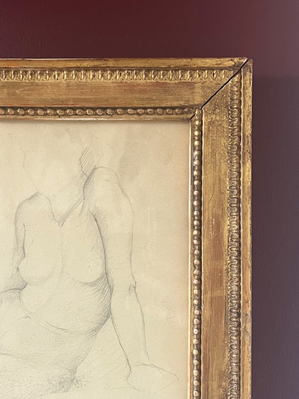 A pencil life drawing depicting a seated female nude, displayed inside a gilded wood frame with decorative beaded details. View XI