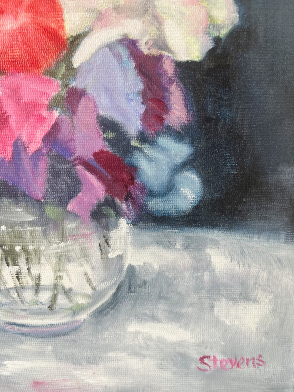 A framed oil painting depicting a colourful bouquet of pink, red, and purple sweet peas in a clear glass vase set against a dark blue background. View X