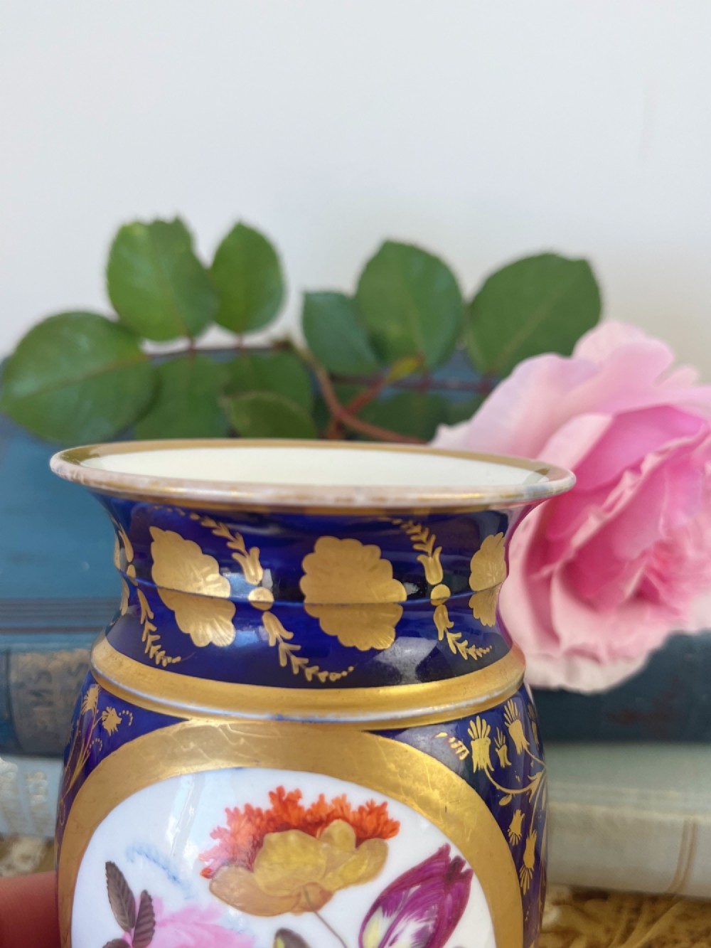 A small cylindrical Regency Coalport porcelain spill vase featuring a cobalt blue ground with gold leaf accents and a central oval medallion hand-painted with flowers. View VI