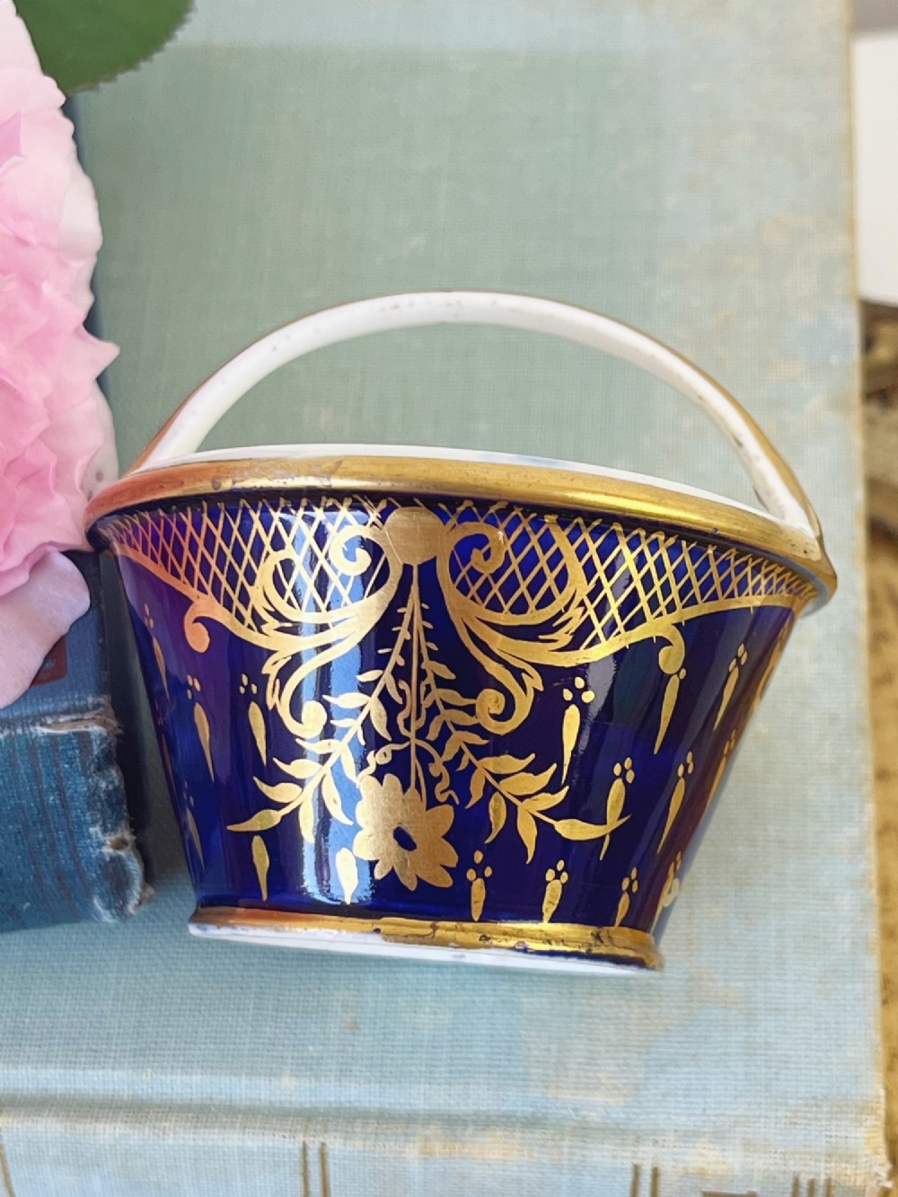 A miniature Regency Coalport porcelain basket featuring an overhead gilt handle, cobalt blue exterior casing with a hand-painted floral reserve, and a plain white interior. View IV