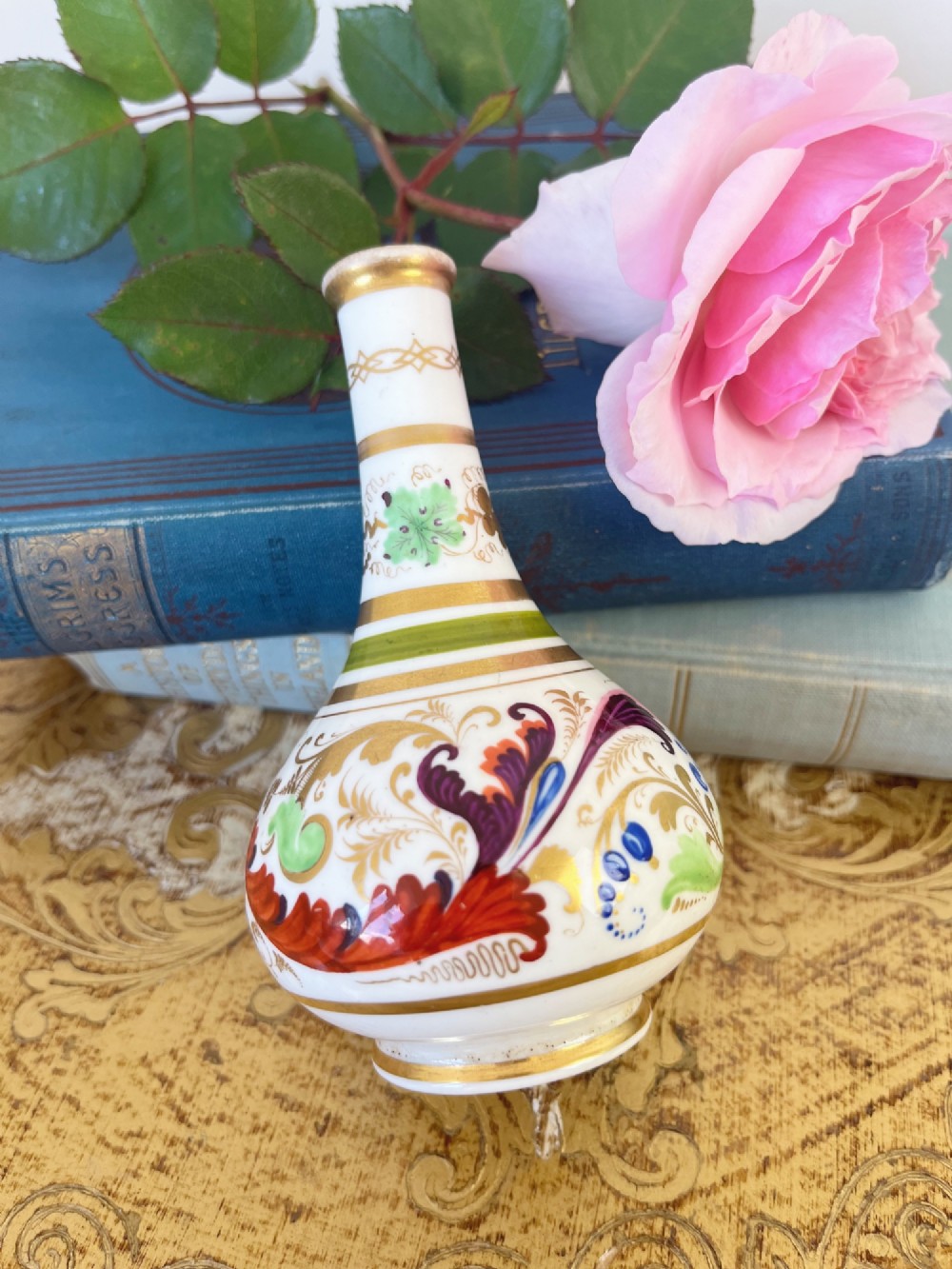 A small Georgian porcelain bud vase featuring a rounded base and narrow neck with hand-painted polychrome scroll motifs and gilded bands. View II