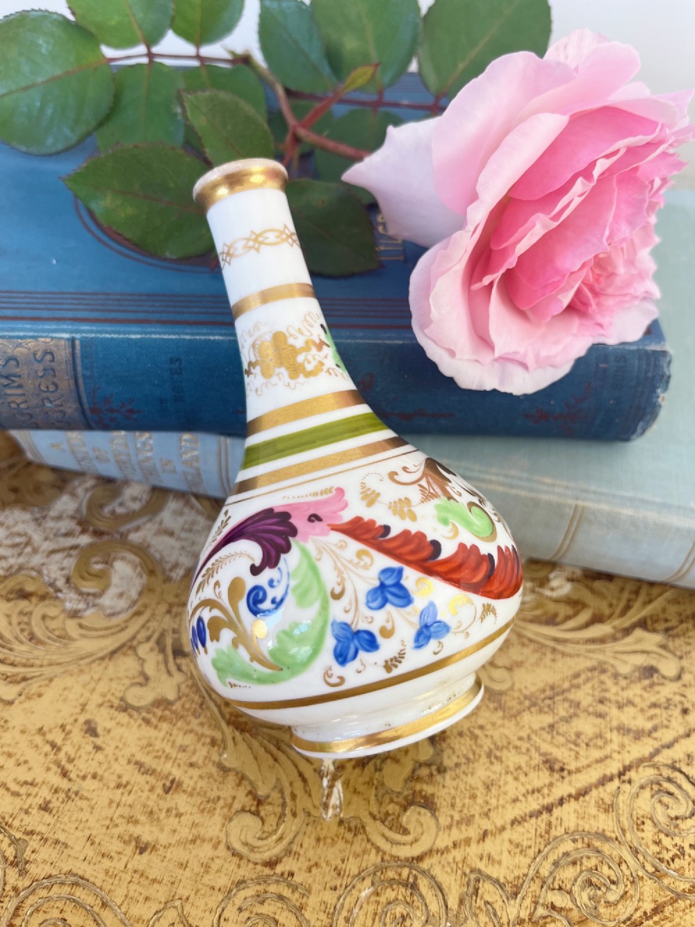 A small Georgian porcelain bud vase featuring a rounded base and narrow neck with hand-painted polychrome scroll motifs and gilded bands. View III