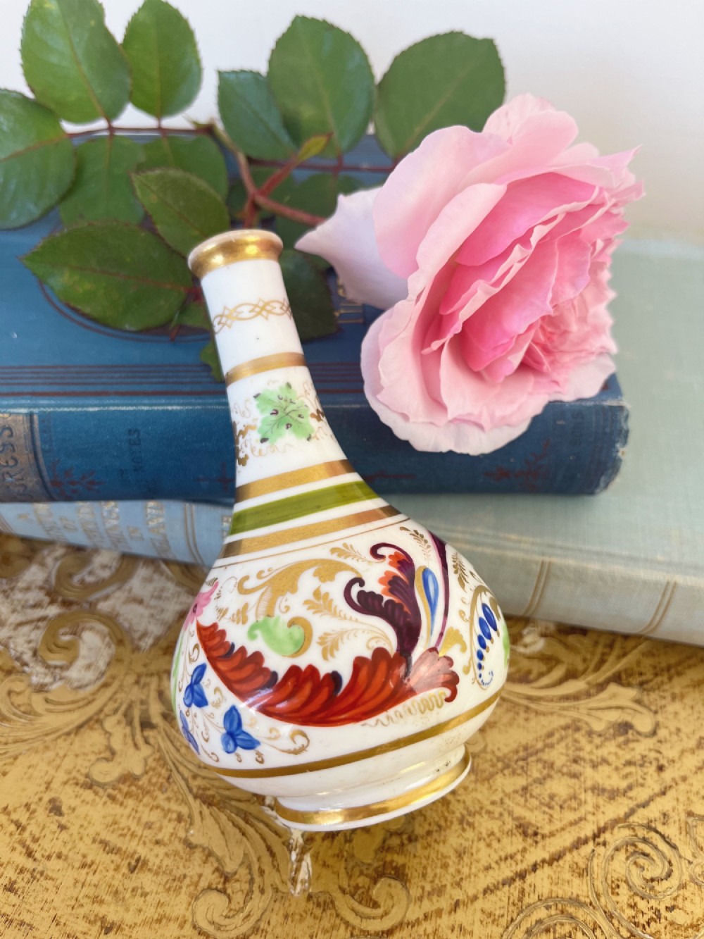 A small Georgian porcelain bud vase featuring a rounded base and narrow neck with hand-painted polychrome scroll motifs and gilded bands. View IV