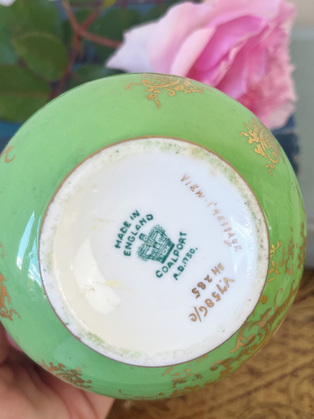 An apple green ceramic miniature vase featuring gilded handles, gold scrollwork accents, and a hand-painted landscape scene inside a central circular medallion. View VII