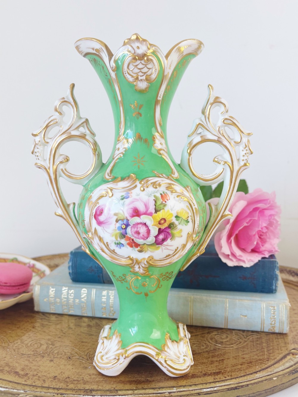 An apple green Rococo Revival porcelain vase featuring ornate gilded scroll handles, a quad-lobed pedestal base, and a central handpainted floral medallion on a white background. View II