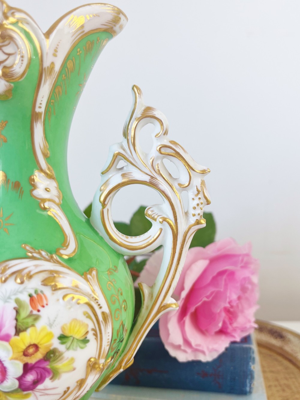 An apple green Rococo Revival porcelain vase featuring ornate gilded scroll handles, a quad-lobed pedestal base, and a central handpainted floral medallion on a white background. View III