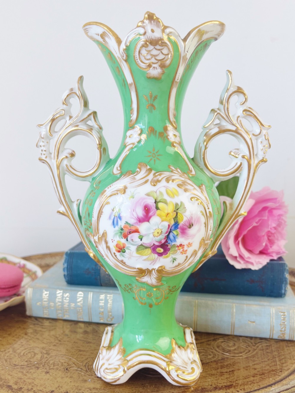 An apple green Rococo Revival porcelain vase featuring ornate gilded scroll handles, a quad-lobed pedestal base, and a central handpainted floral medallion on a white background. View VIII