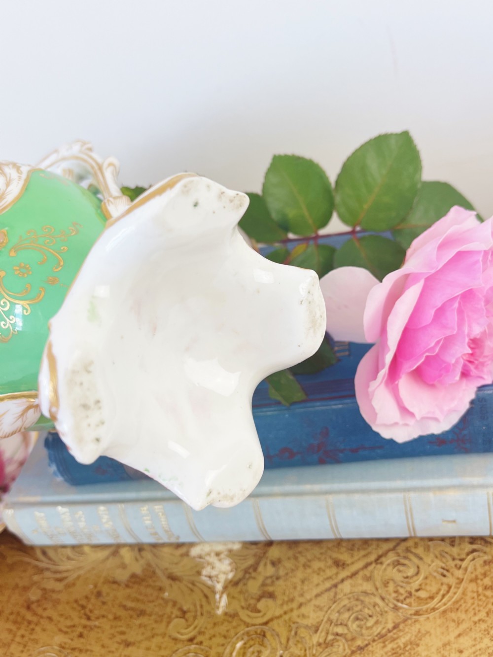 An apple green Rococo Revival porcelain vase featuring ornate gilded scroll handles, a quad-lobed pedestal base, and a central handpainted floral medallion on a white background. View XI