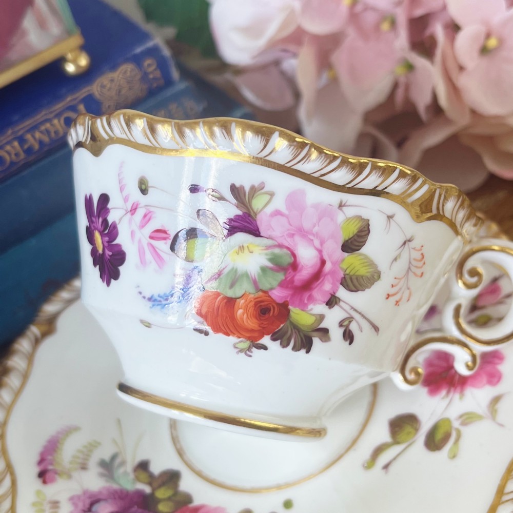 A white porcelain teacup and saucer set featuring hand-painted floral motifs, a gadrooned rim, and gilded scroll accents. View III