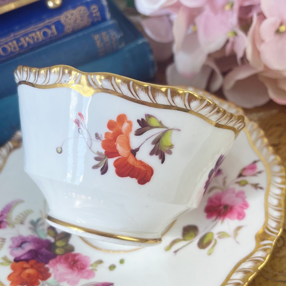 A white porcelain teacup and saucer set featuring hand-painted floral motifs, a gadrooned rim, and gilded scroll accents. View IV