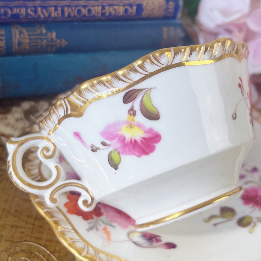 A white porcelain teacup and saucer set featuring hand-painted floral motifs, a gadrooned rim, and gilded scroll accents. View V