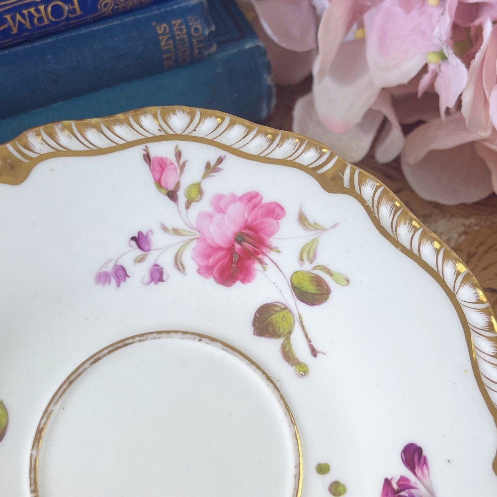 A white porcelain teacup and saucer set featuring hand-painted floral motifs, a gadrooned rim, and gilded scroll accents. View VII