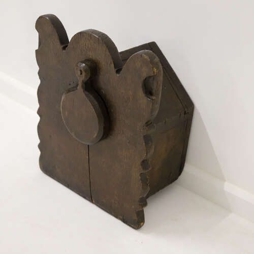 fig 4. A dark oak wall-mounted salt box featuring shaped decorative edges, a circular hanging aperture, and a hinged lid.