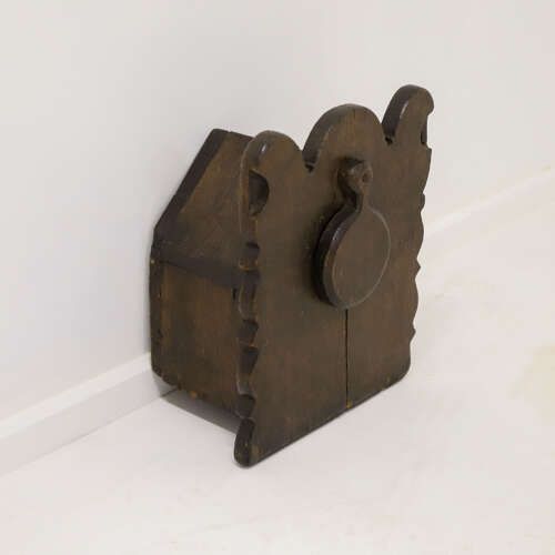 fig 5. A dark oak wall-mounted salt box featuring shaped decorative edges, a circular hanging aperture, and a hinged lid.