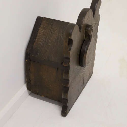 fig 6. A dark oak wall-mounted salt box featuring shaped decorative edges, a circular hanging aperture, and a hinged lid.