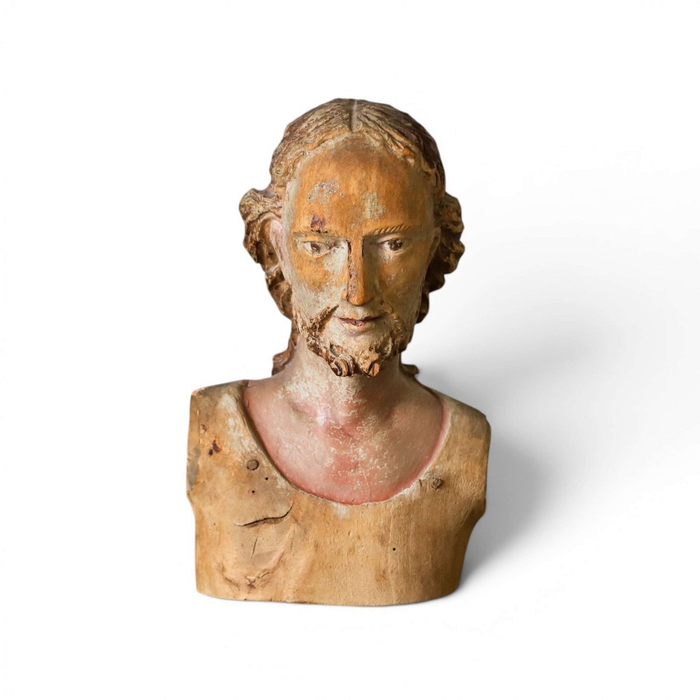 An 18th-century carved olive wood bust depicting Christ with visible traces of original polychrome paint.