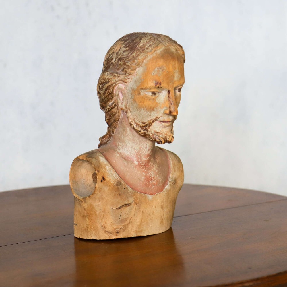 An 18th-century carved olive wood bust depicting Christ with visible traces of original polychrome paint. View IV