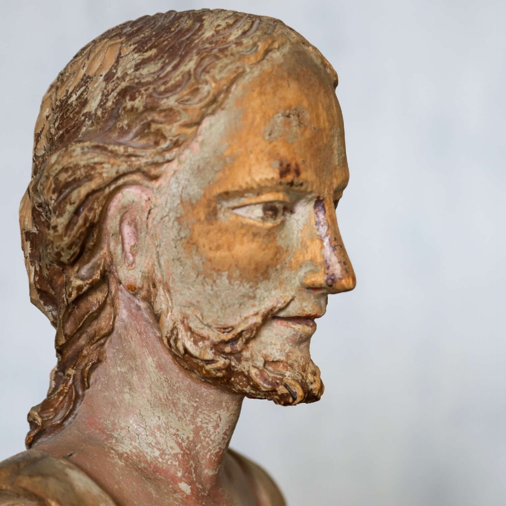 An 18th-century carved olive wood bust depicting Christ with visible traces of original polychrome paint. View IX