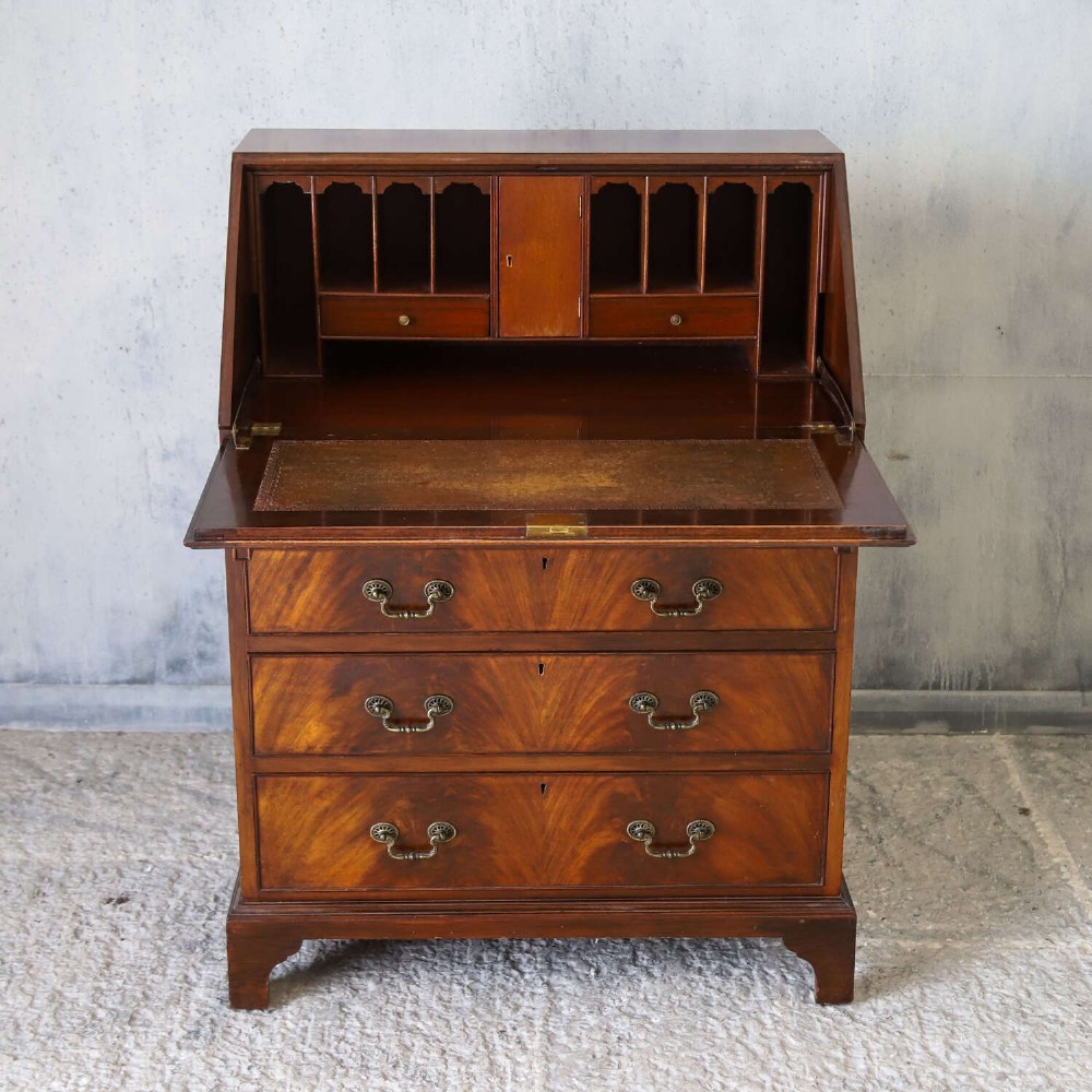 An English 1930s flame mahogany slant-front writing bureau featuring four lower drawers and brass handles. View III
