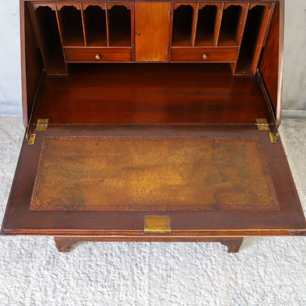 An English 1930s flame mahogany slant-front writing bureau featuring four lower drawers and brass handles. View IV