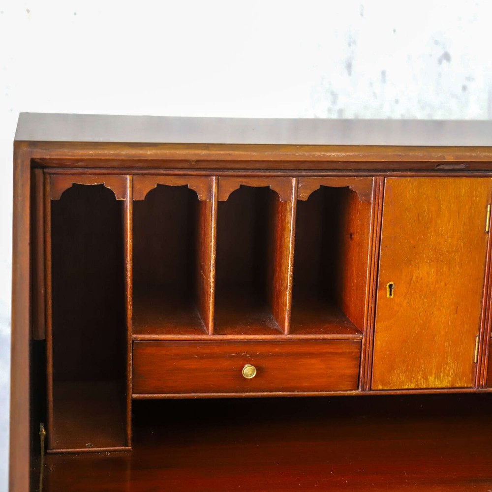 An English 1930s flame mahogany slant-front writing bureau featuring four lower drawers and brass handles. View V
