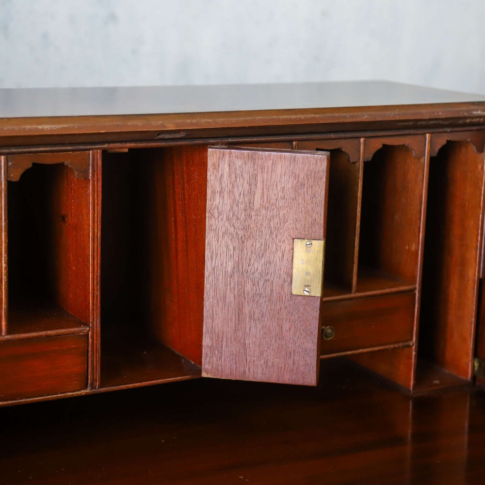 An English 1930s flame mahogany slant-front writing bureau featuring four lower drawers and brass handles. View VI