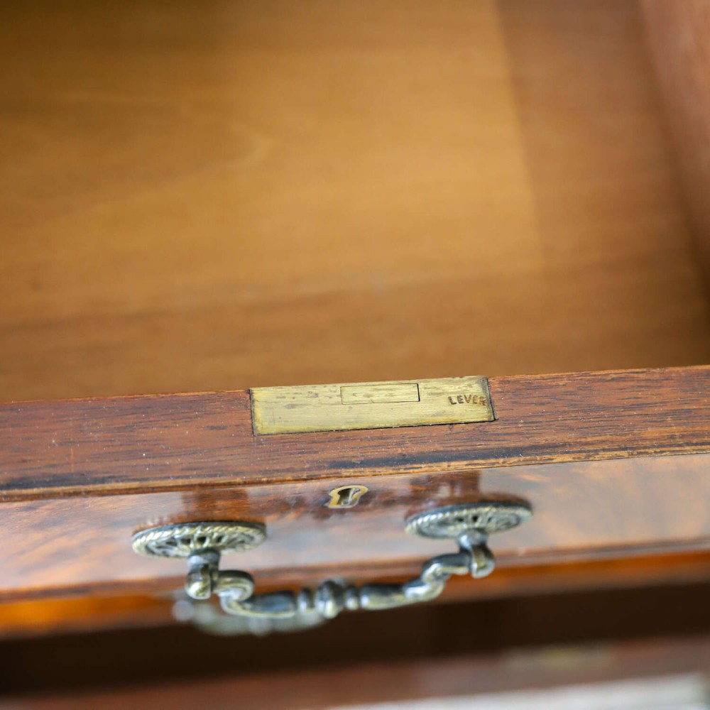An English 1930s flame mahogany slant-front writing bureau featuring four lower drawers and brass handles. View XII
