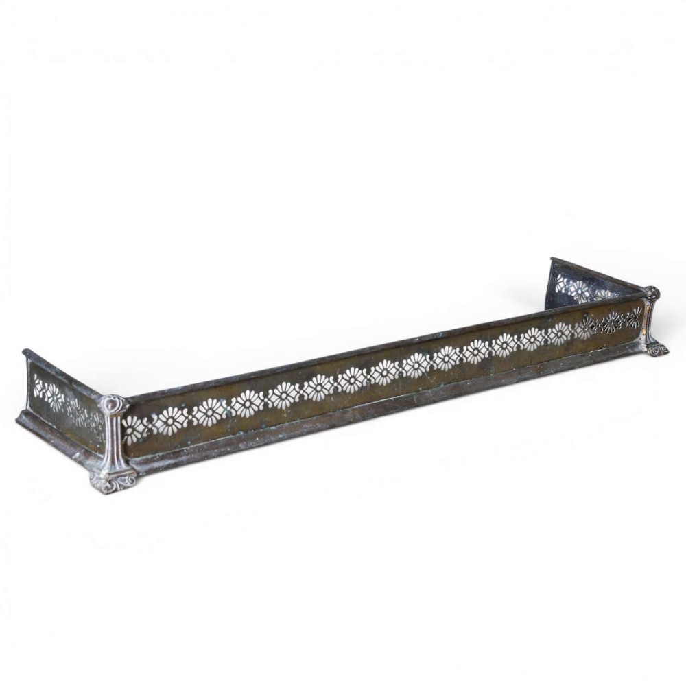 An English Art Nouveau fireplace fender constructed from brass and steel featuring a continuous pierced daisy motif.