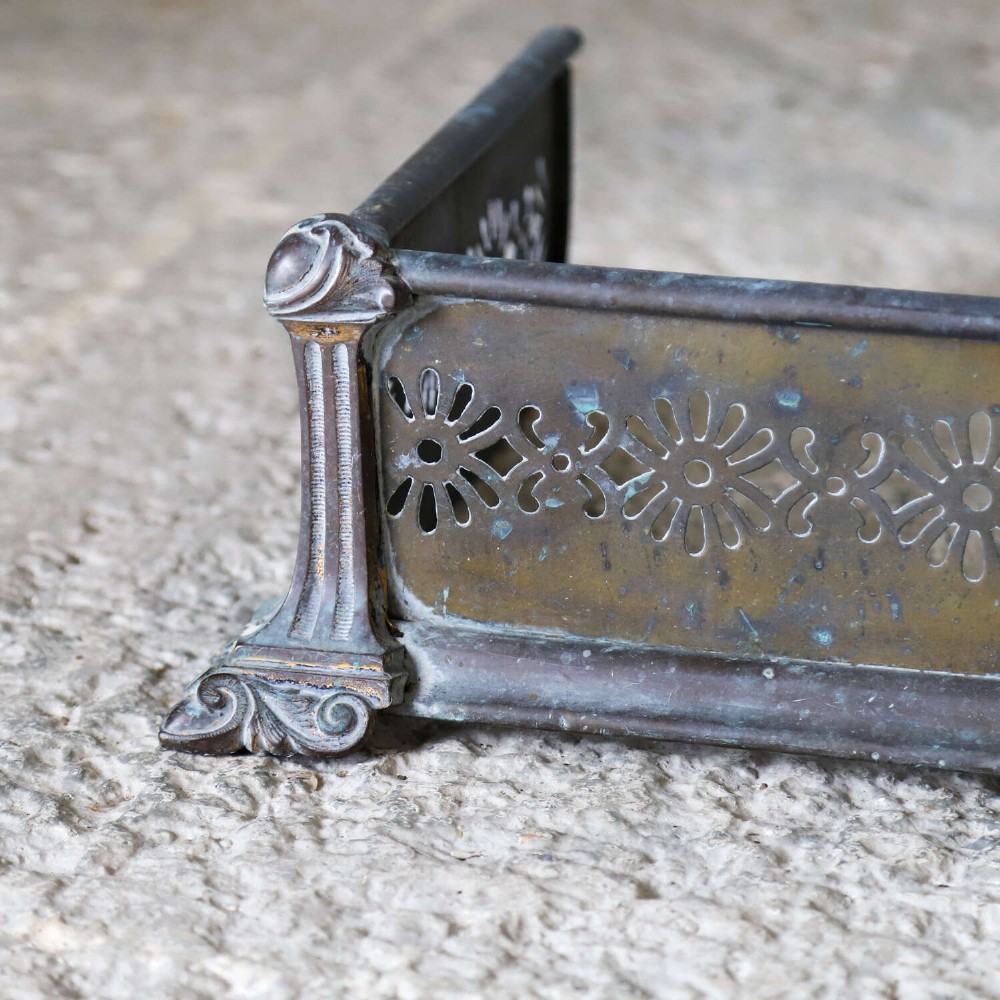 An English Art Nouveau fireplace fender constructed from brass and steel featuring a continuous pierced daisy motif. View V