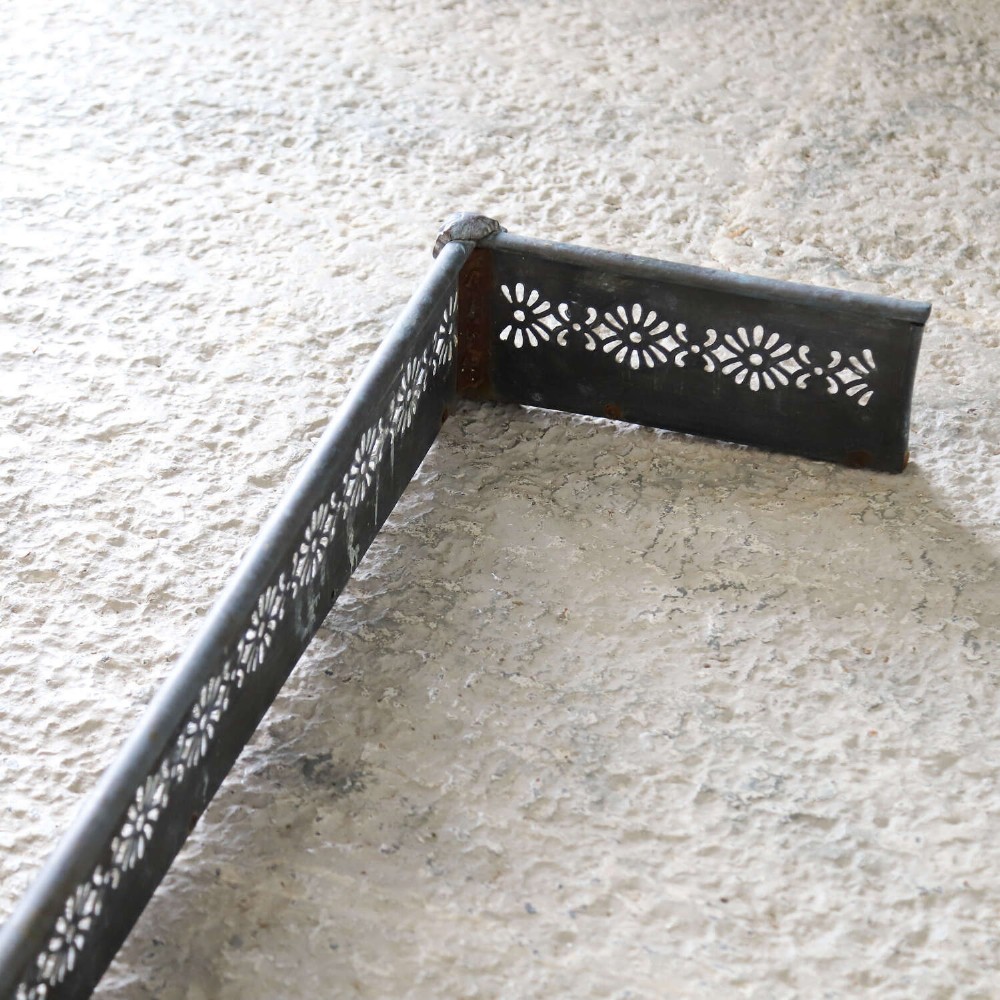 An English Art Nouveau fireplace fender constructed from brass and steel featuring a continuous pierced daisy motif. View IX