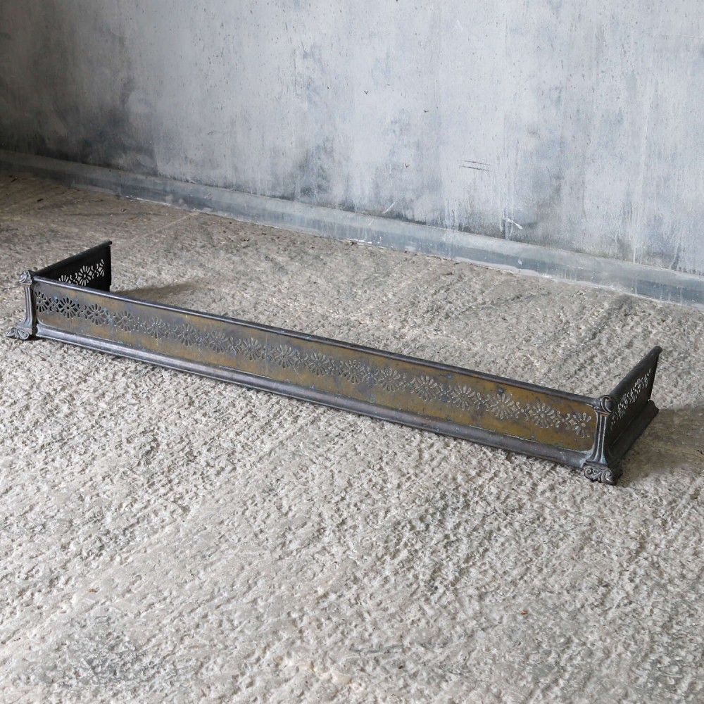 An English Art Nouveau fireplace fender constructed from brass and steel featuring a continuous pierced daisy motif. View X