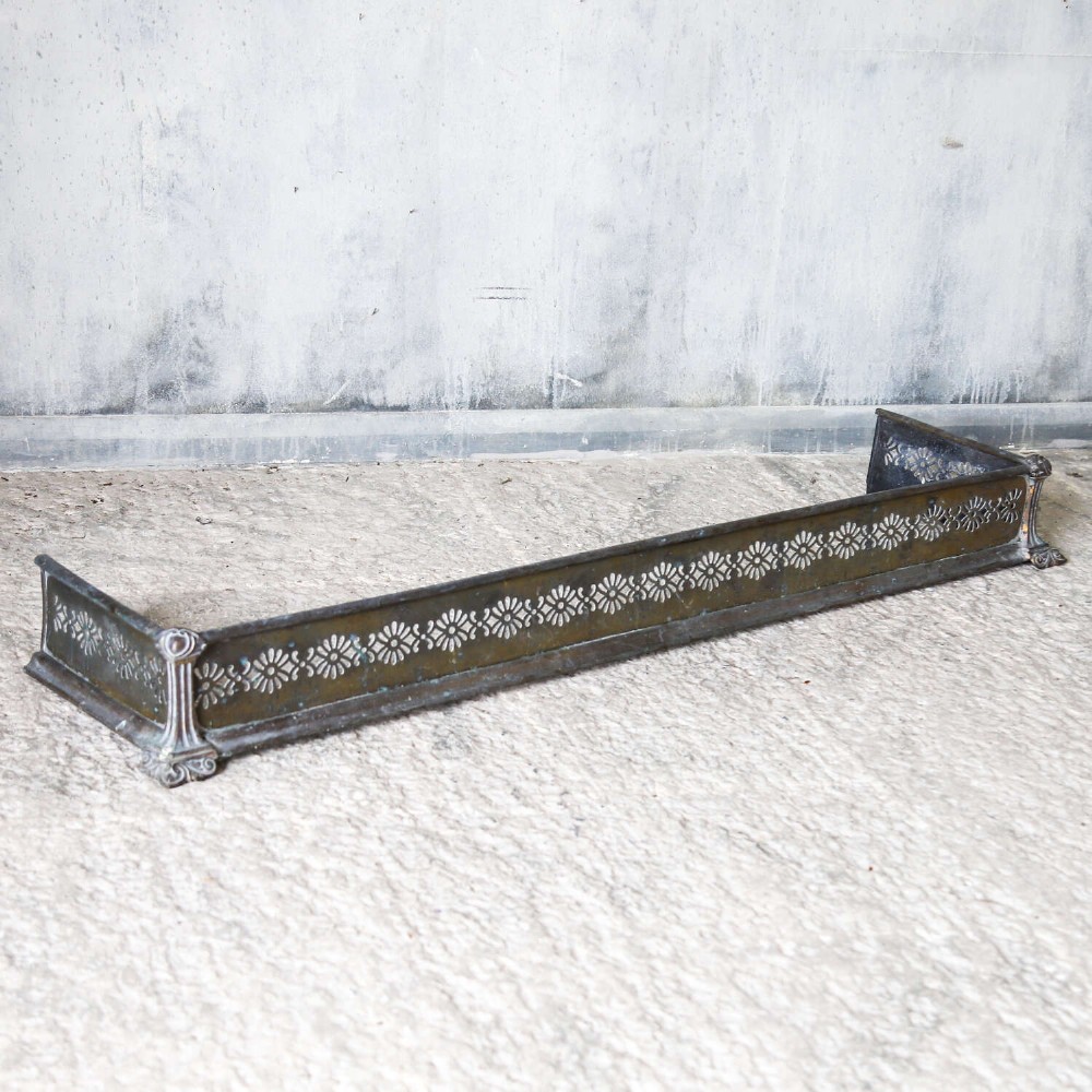 An English Art Nouveau fireplace fender constructed from brass and steel featuring a continuous pierced daisy motif. View XII