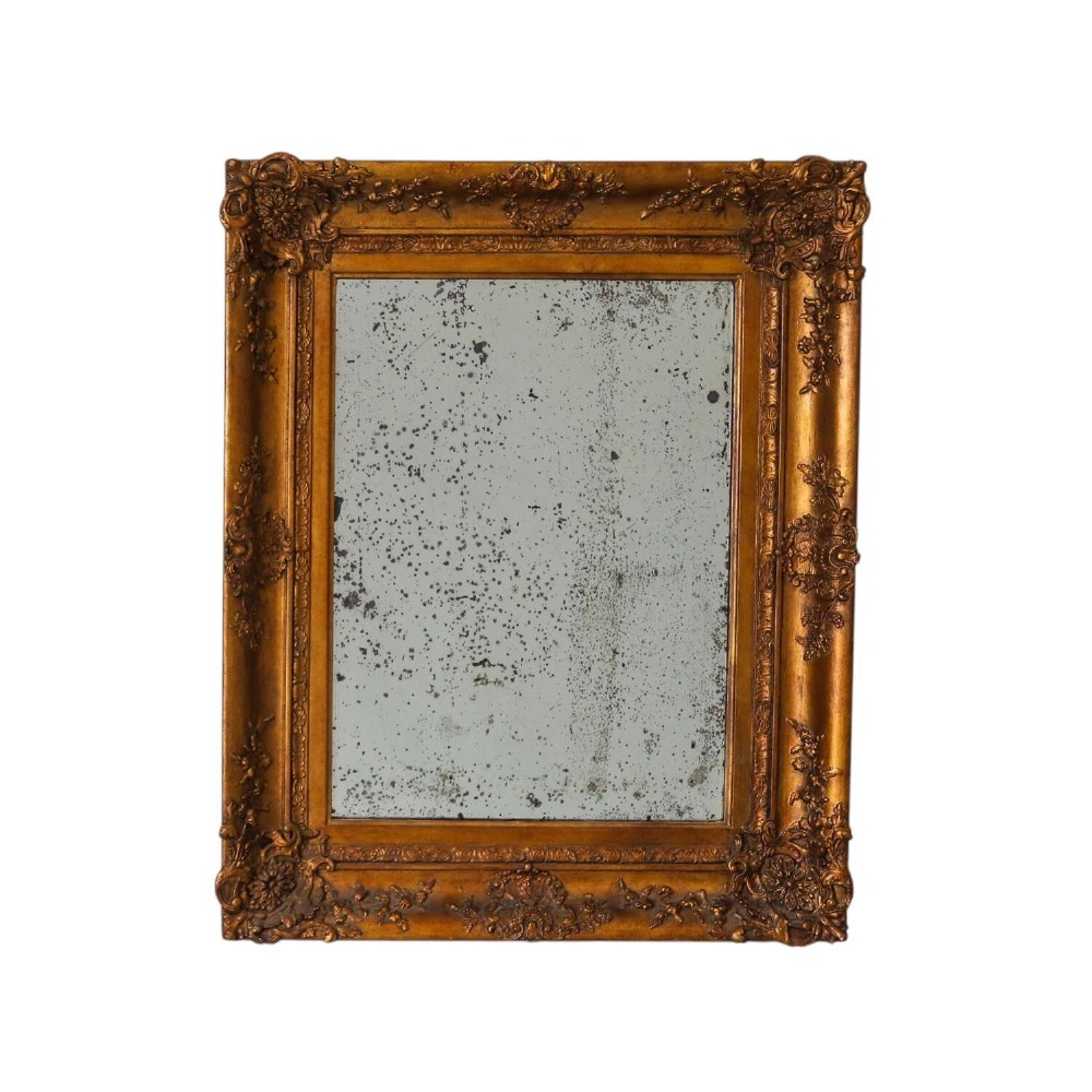 An early 19th-century rectangular wall mirror featuring an ornate gold gilded frame with scrollwork moulding and heavily foxed glass.