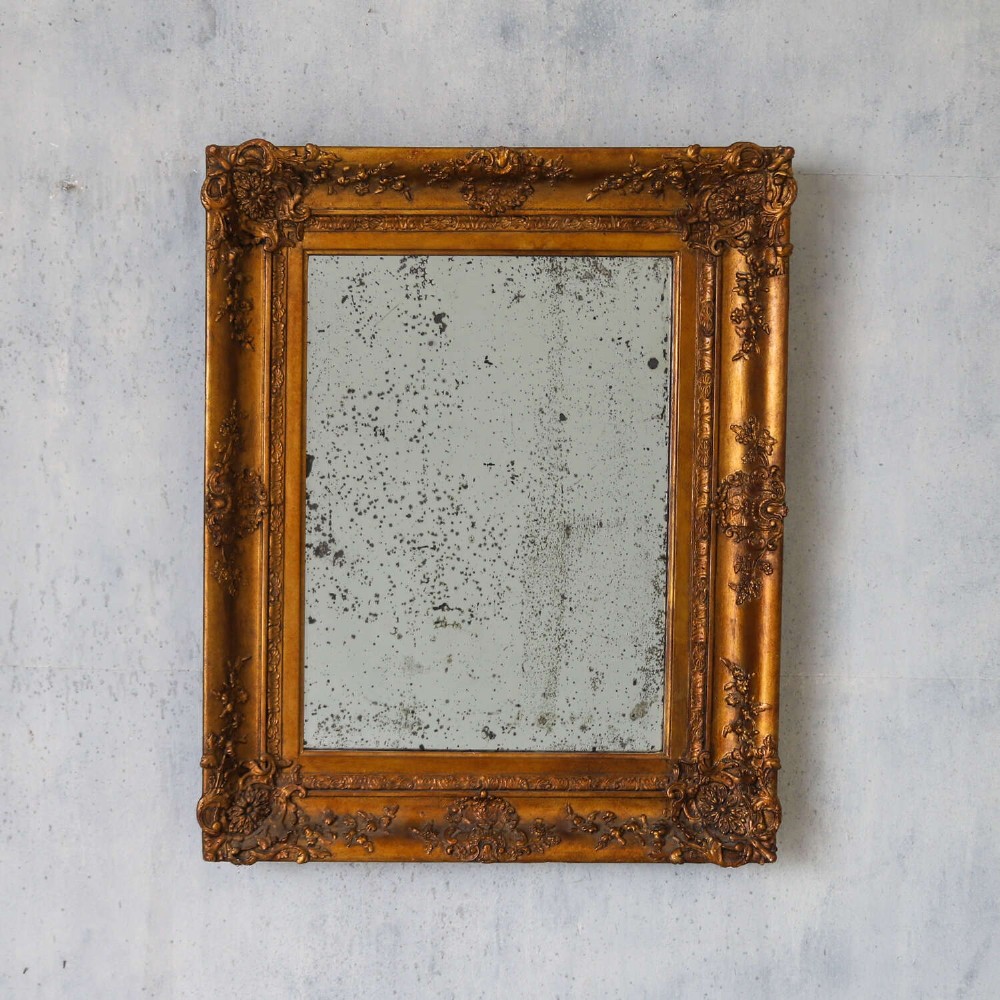 An early 19th-century rectangular wall mirror featuring an ornate gold gilded frame with scrollwork moulding and heavily foxed glass. View II