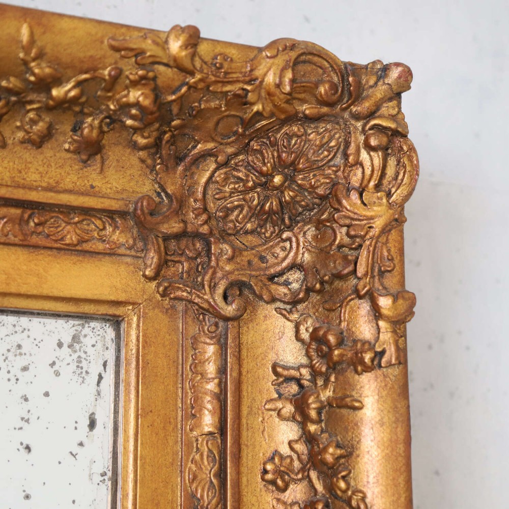 An early 19th-century rectangular wall mirror featuring an ornate gold gilded frame with scrollwork moulding and heavily foxed glass. View V