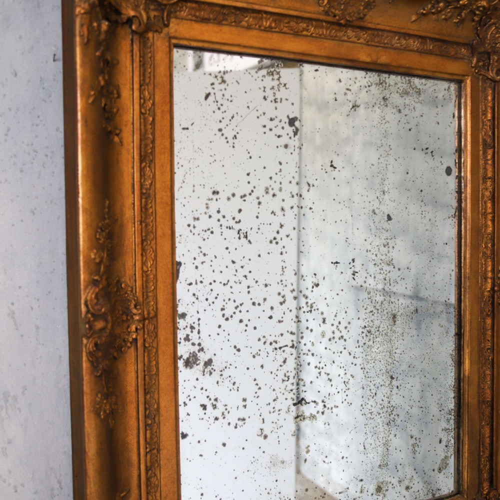 An early 19th-century rectangular wall mirror featuring an ornate gold gilded frame with scrollwork moulding and heavily foxed glass. View VI