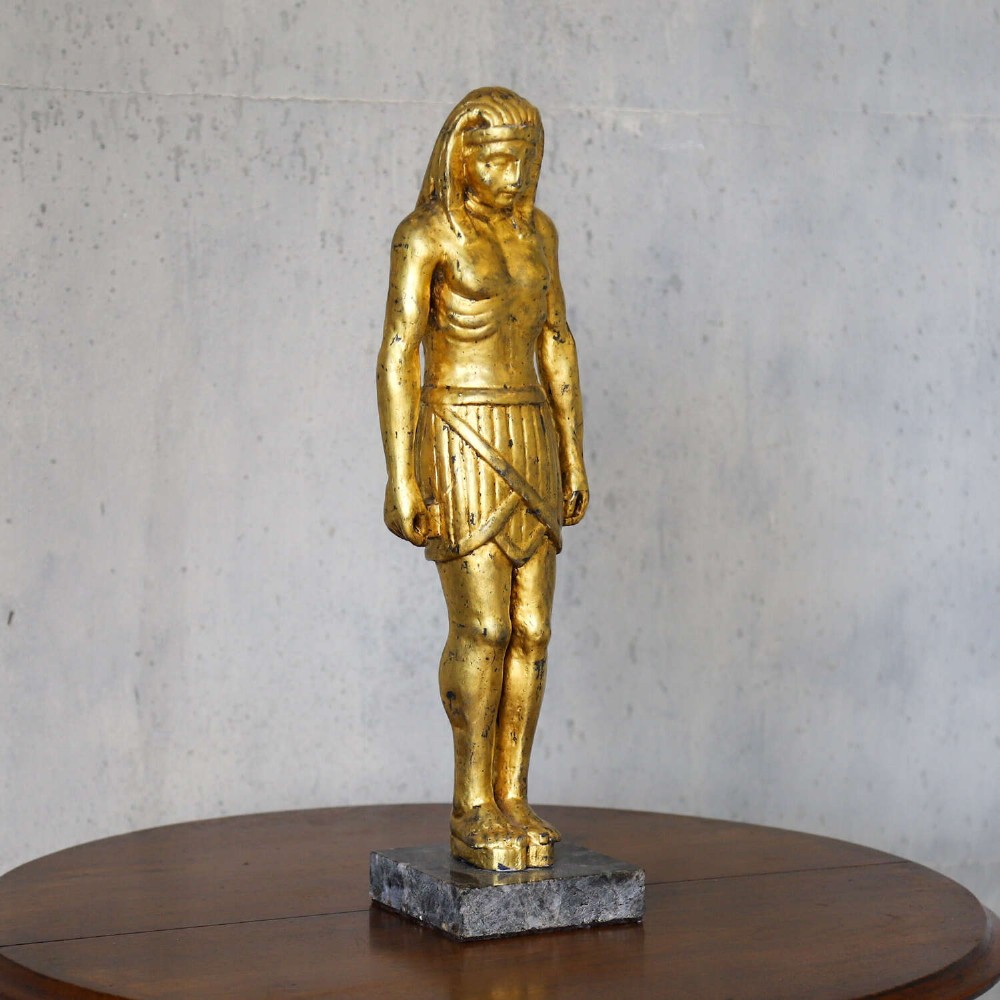 A 19th-century Egyptian Revival gilt wooden standing figure mounted on a dark square stone base. View III