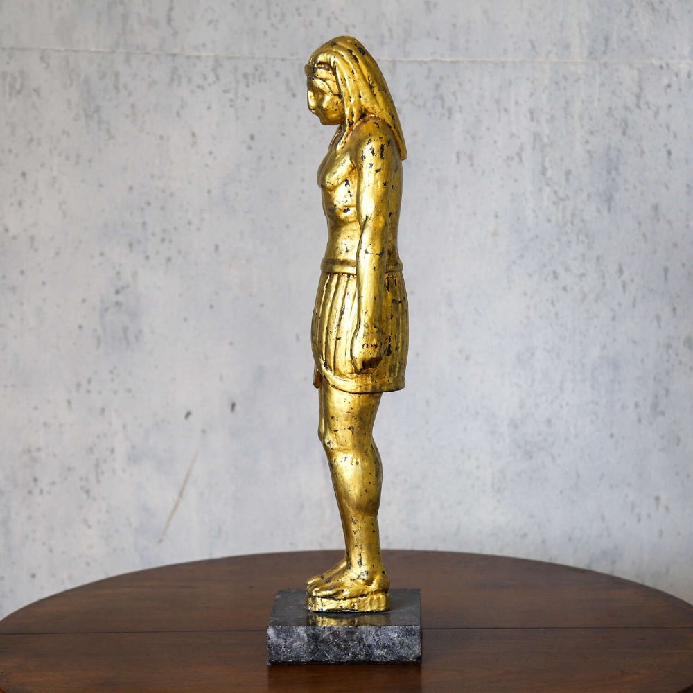 A 19th-century Egyptian Revival gilt wooden standing figure mounted on a dark square stone base. View VI
