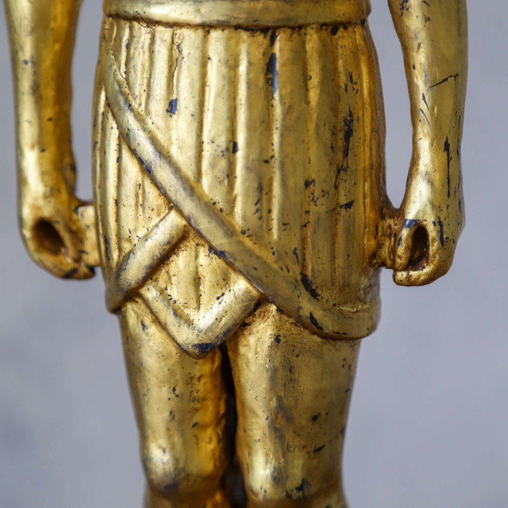 A 19th-century Egyptian Revival gilt wooden standing figure mounted on a dark square stone base. View IX