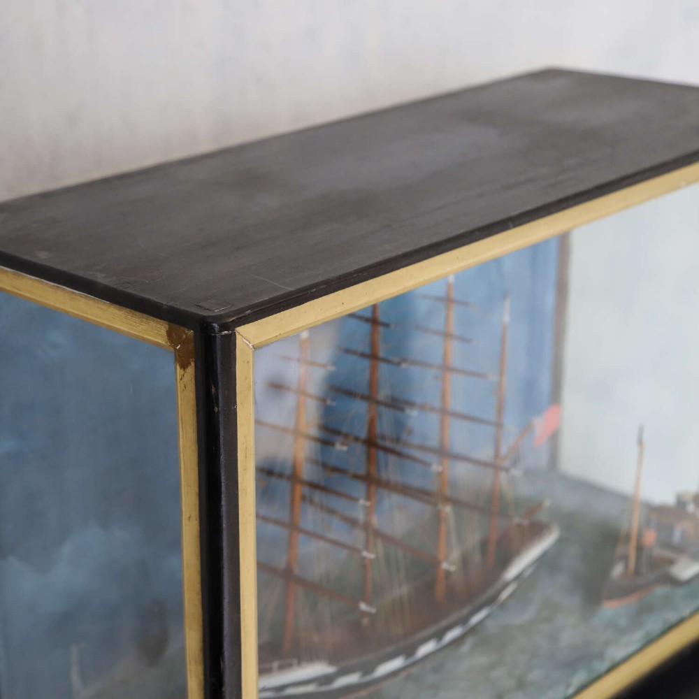 A glazed wooden shadow box containing a three-dimensional diorama of a four-masted sailing ship and a steam barge against a painted blue background. View VIII