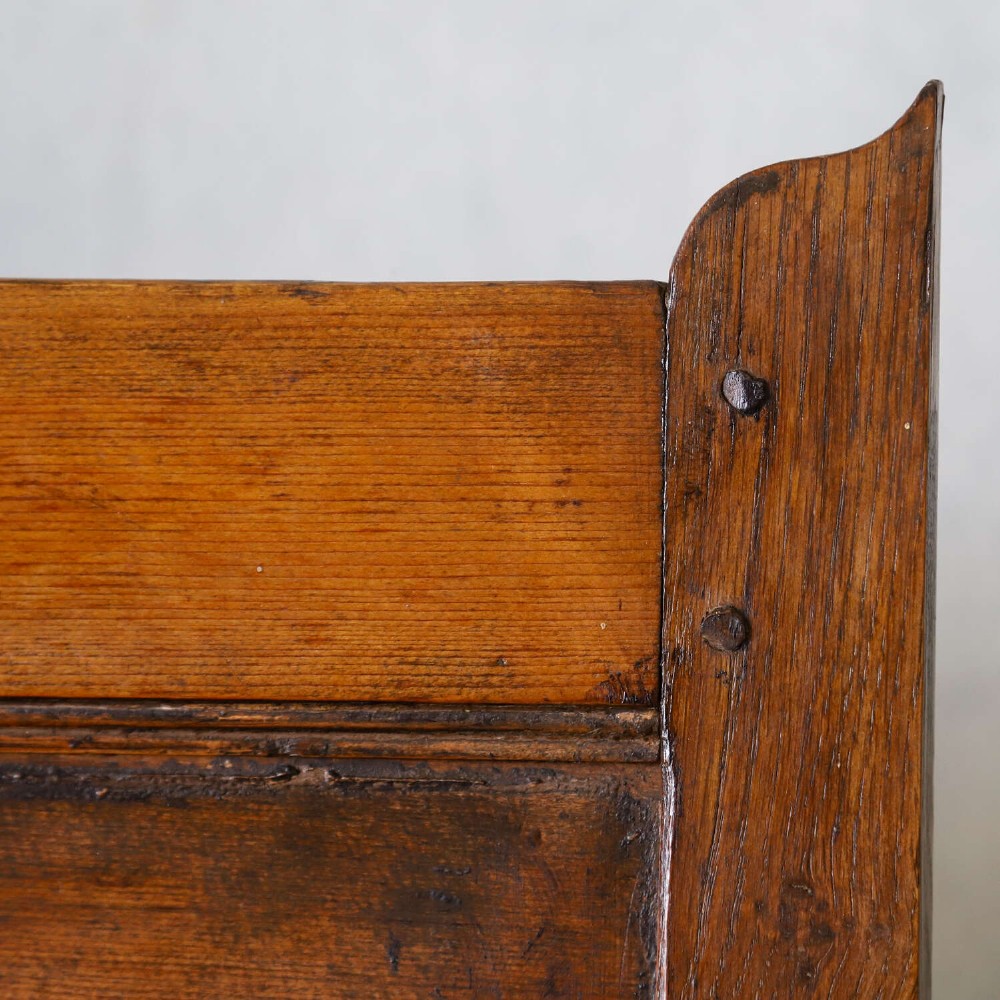 A high-backed antique wooden settle featuring raised timber panels, flat armrests with turned supports, and an enclosed panelled base. View IX