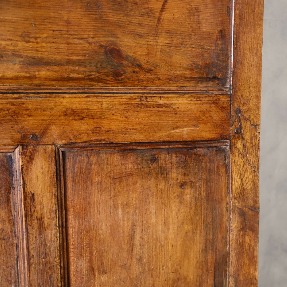 A high-backed antique wooden settle featuring raised timber panels, flat armrests with turned supports, and an enclosed panelled base. View X