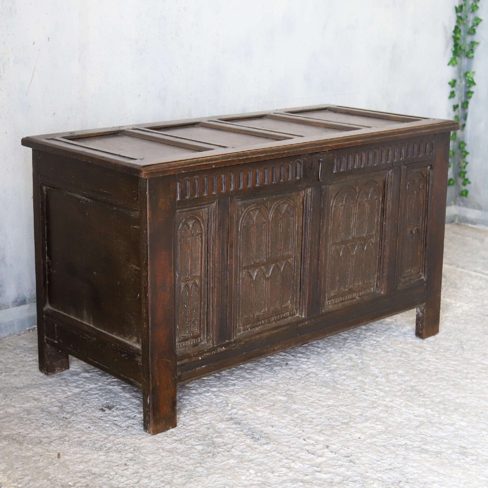 A dark oak coffer featuring four hand-carved Gothic arch panels, a fluted frieze, and a sturdy four-panel hinged lid. View II