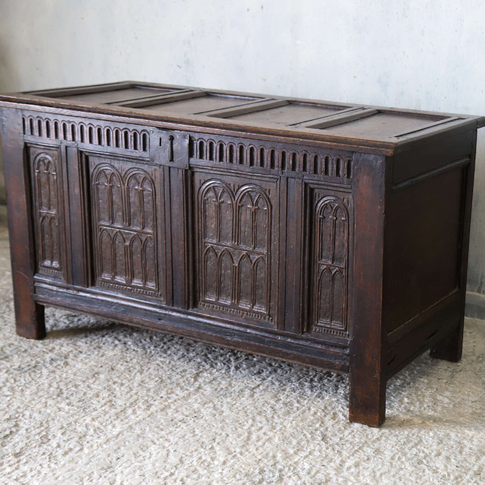 A dark oak coffer featuring four hand-carved Gothic arch panels, a fluted frieze, and a sturdy four-panel hinged lid. View III