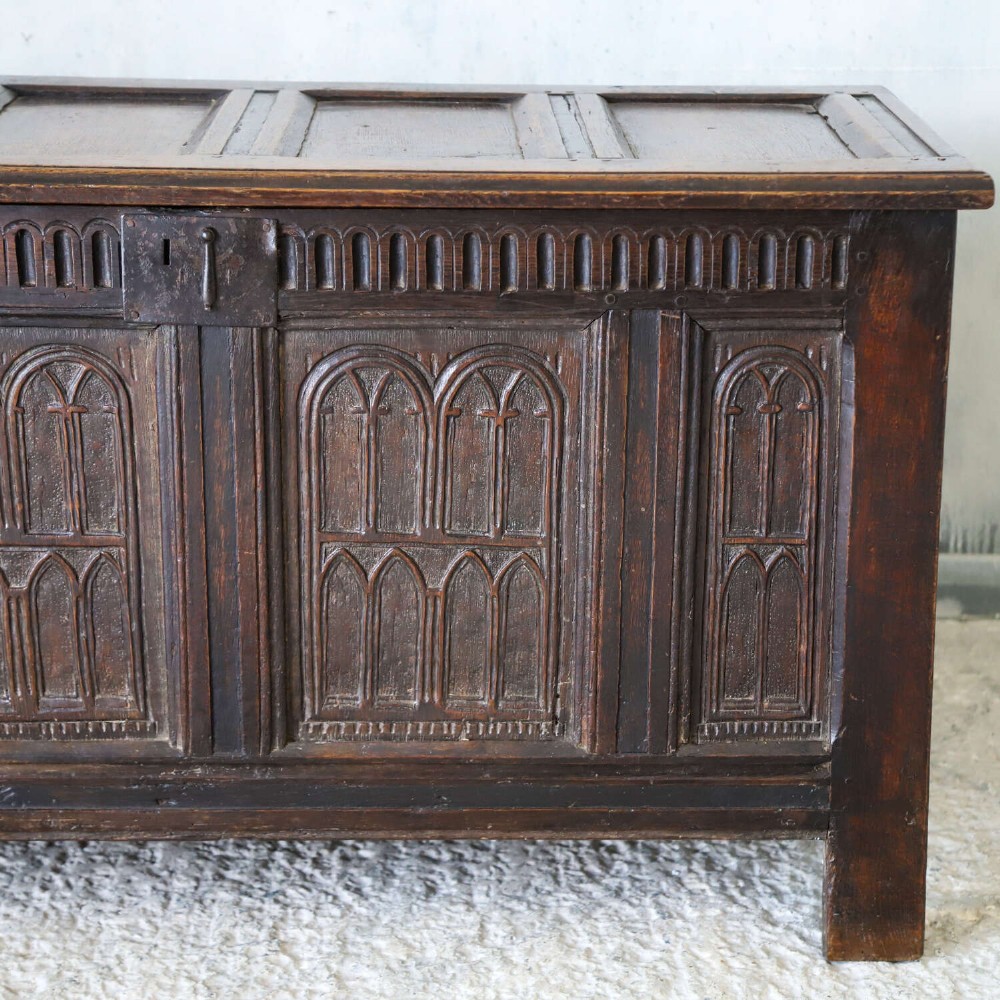 A dark oak coffer featuring four hand-carved Gothic arch panels, a fluted frieze, and a sturdy four-panel hinged lid. View IV